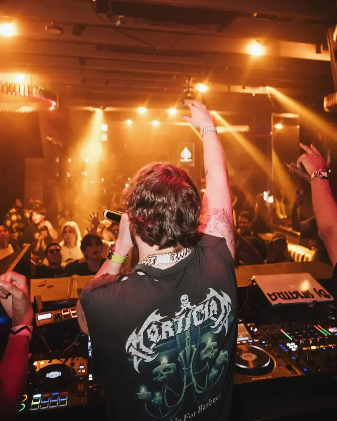 Energetic DJ performing at 1OAK nightclub in Tokyo with a crowd of people.