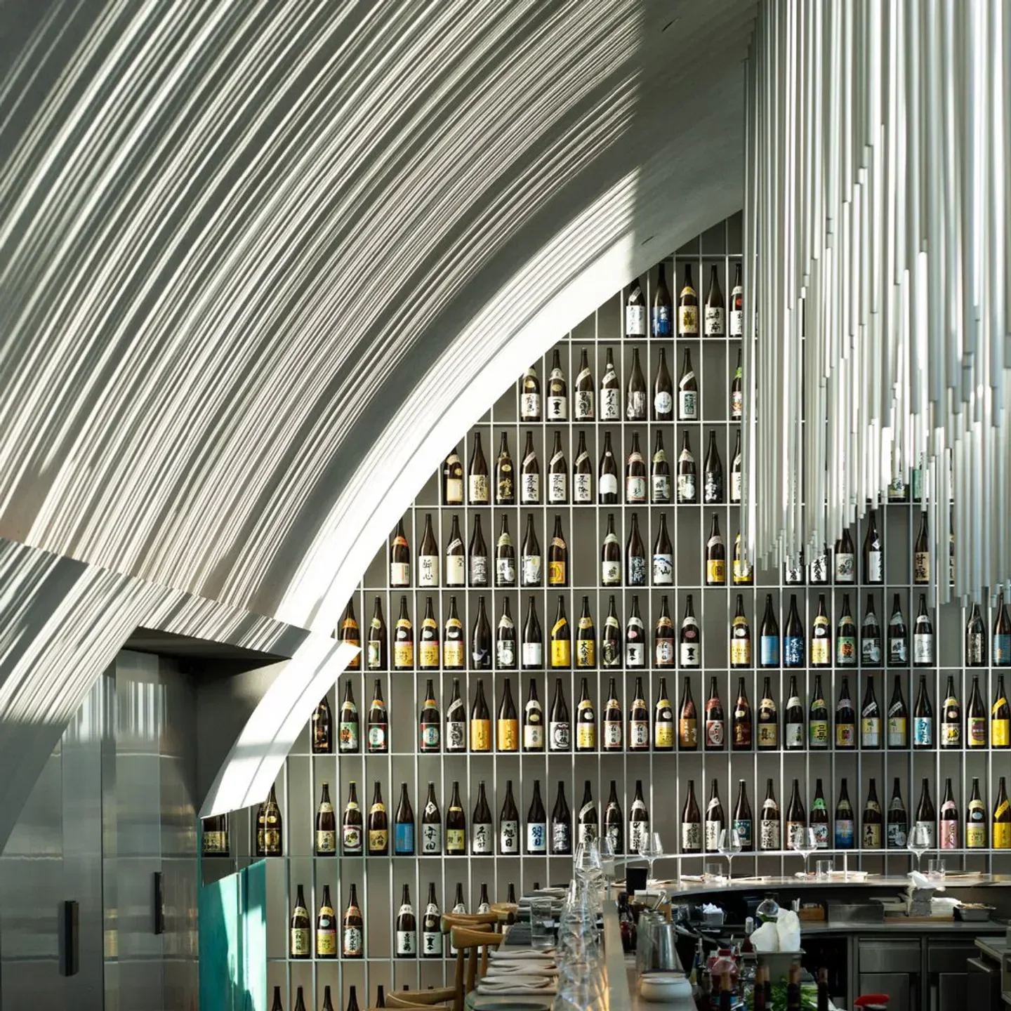 Interior of A by Yuval Ben Neriah restaurant in Tel Aviv, featuring sake bottles and modern design.