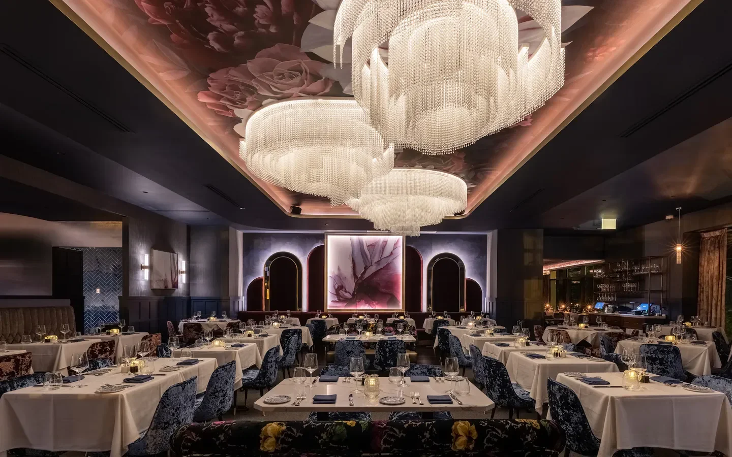 Elegant dining room at Adalina restaurant in Chicago with floral ceiling and chandeliers.