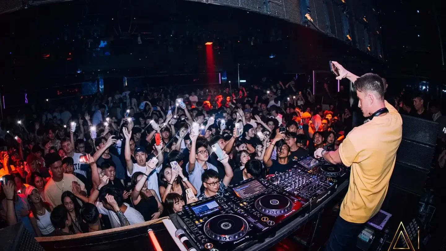DJ at AI Club in Taipei performing for a lively crowd at a packed nightclub