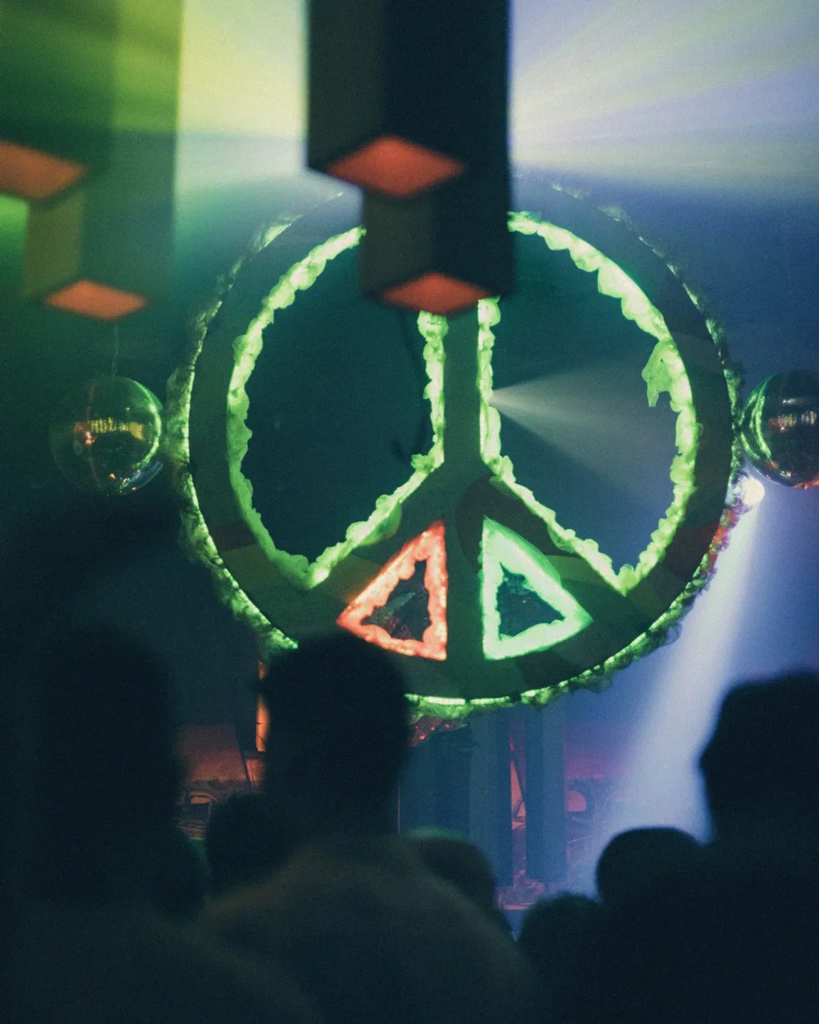 Vibrant peace sign decor illuminated with green and red lights at Akasha nightclub in Ibiza.