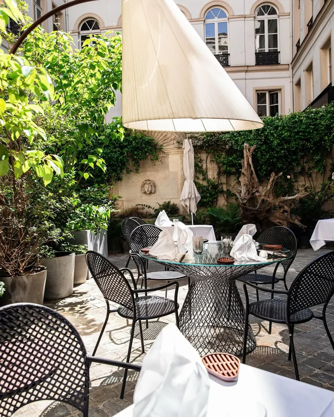Outdoor dining at Akrame in Paris, with tables set and surrounded by lush greenery