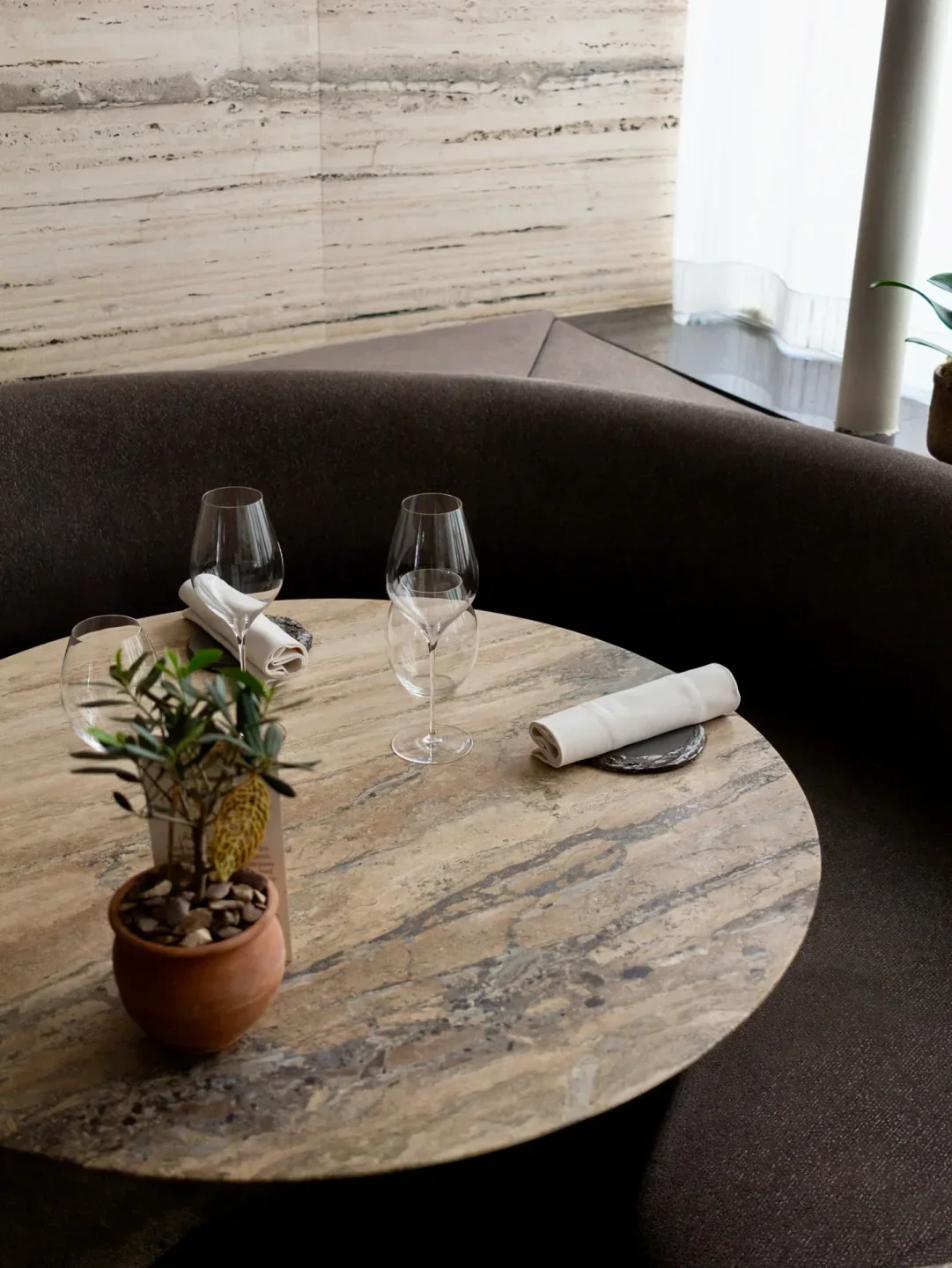 Cozy dining setting at Alan Geaam restaurant in Paris, featuring glasses and a small plant.