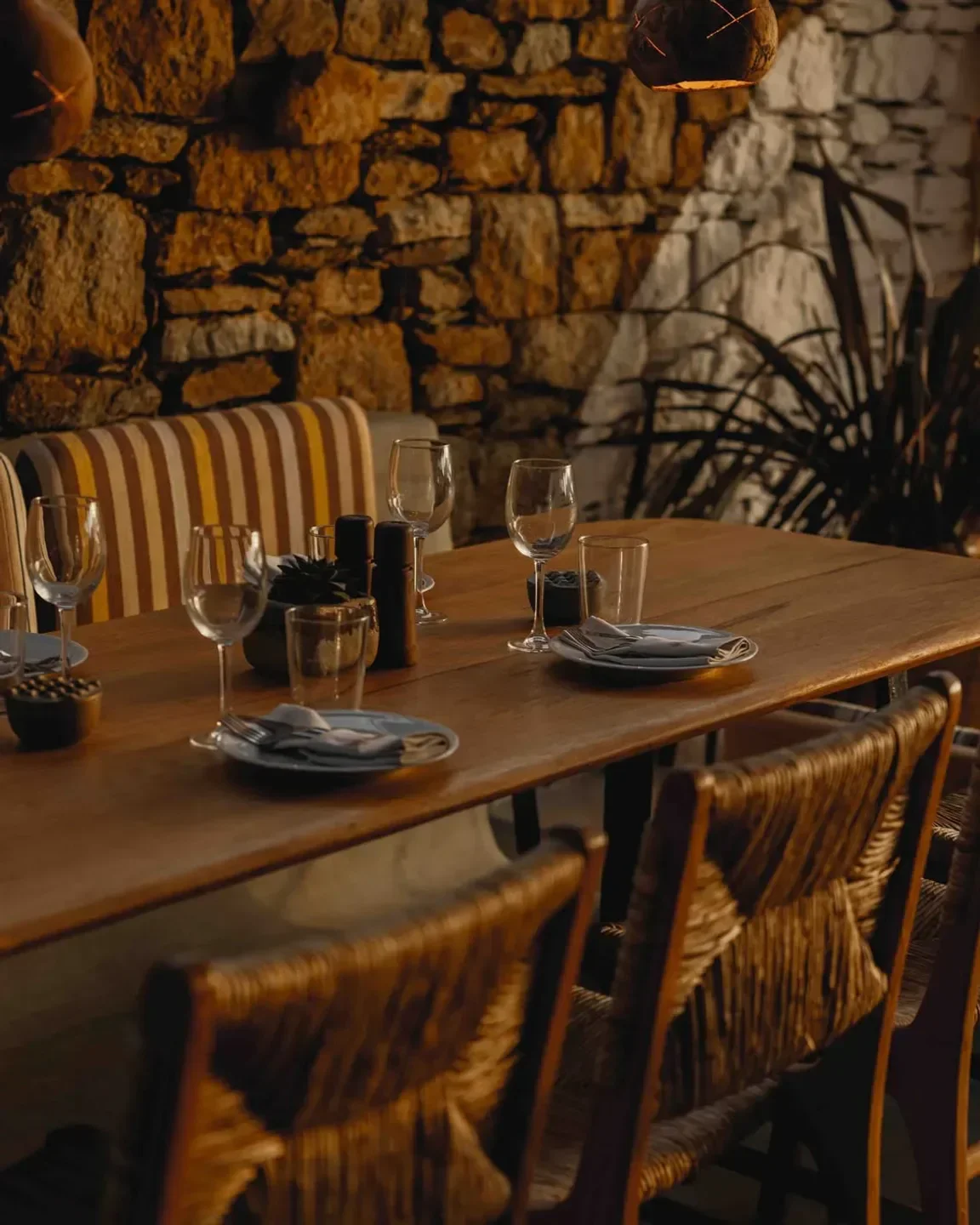 Cozy dining table at Alemagou restaurant in Mykonos, featuring stone wall backdrop.