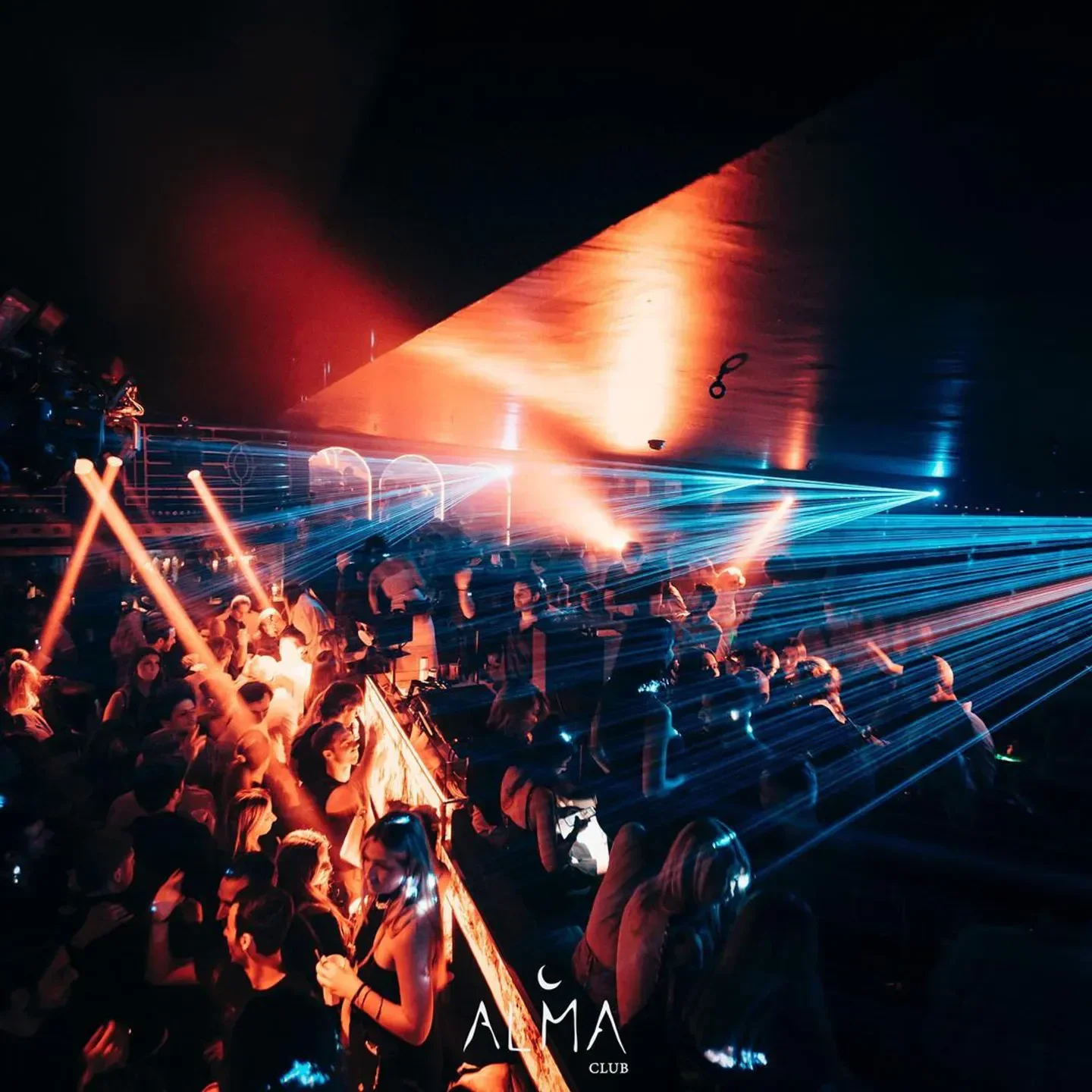 Energetic crowd and laser show inside Alma Club nightclub in Paris, creating a vibrant atmosphere.