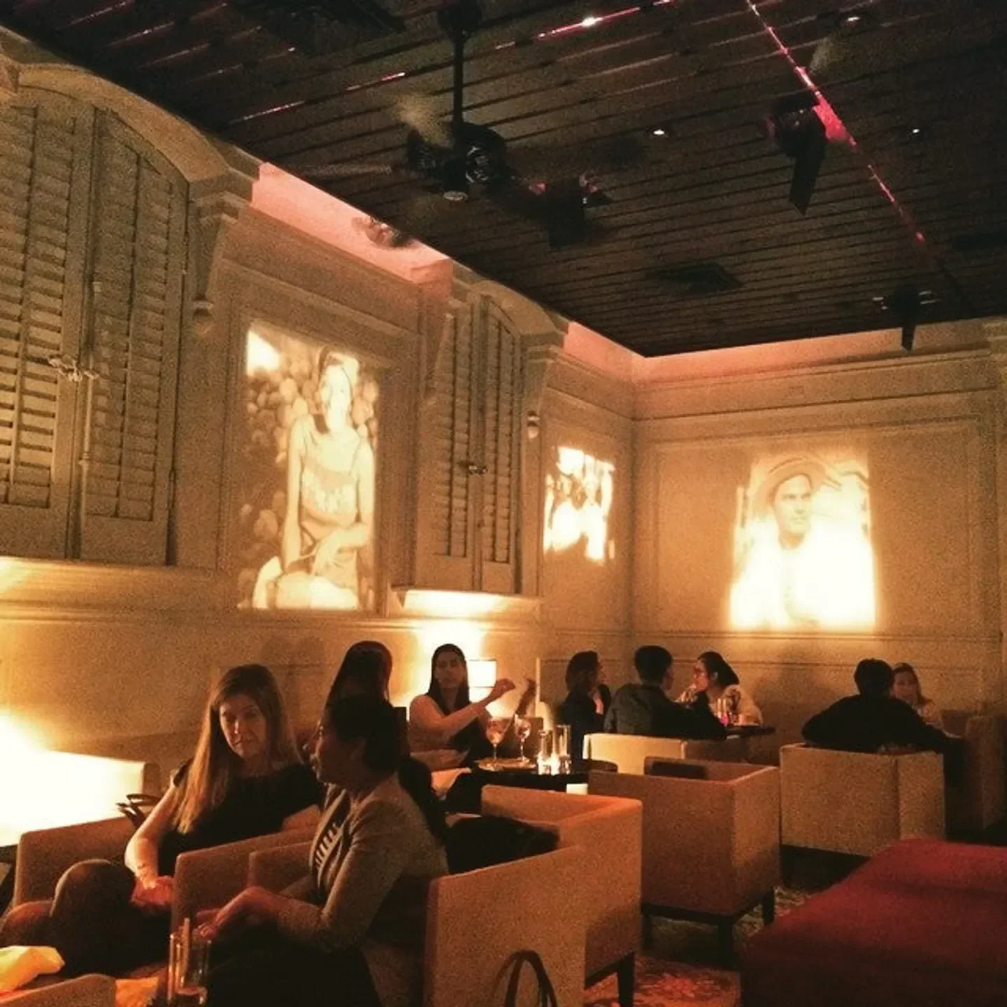 Cozy dining area at Alma de Cuba in Philadelphia, featuring projections and patrons enjoying themselves.