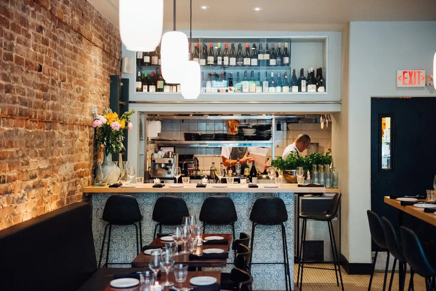 Interior of Alma restaurant in Montreal, featuring bar seating and open kitchen with chefs.