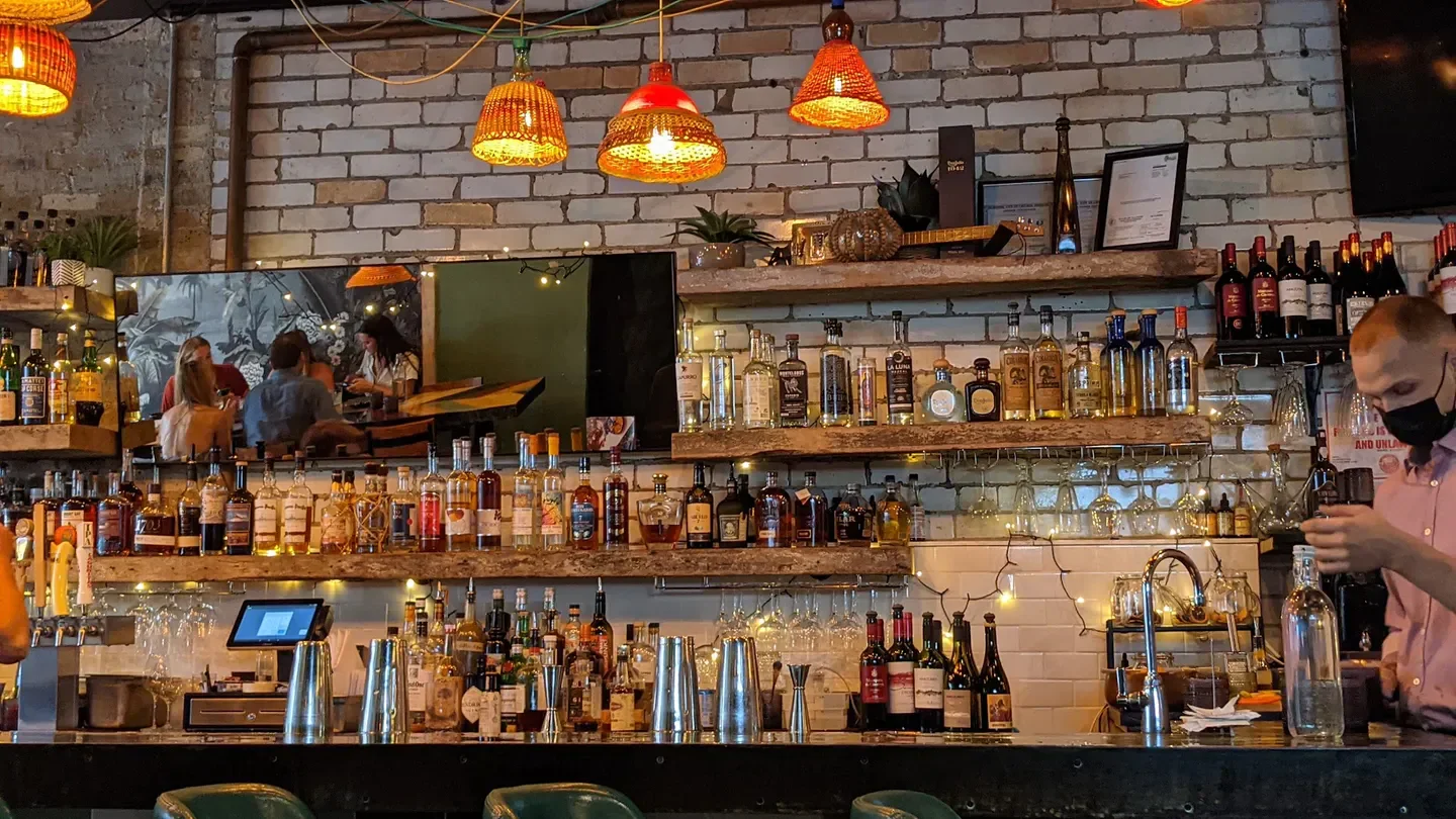 Interior bar scene at Amaru in Chicago, with bottles, lights and patrons.