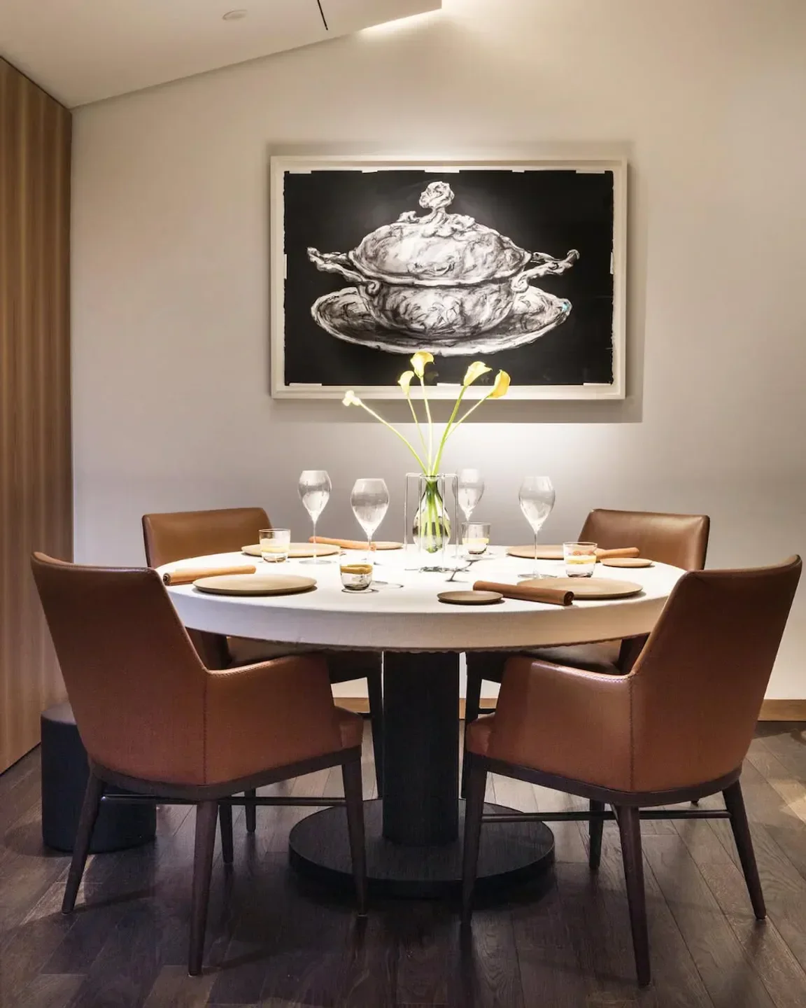 Elegant dining room at Andrea Aprea restaurant in Milan, featuring art and a round table.