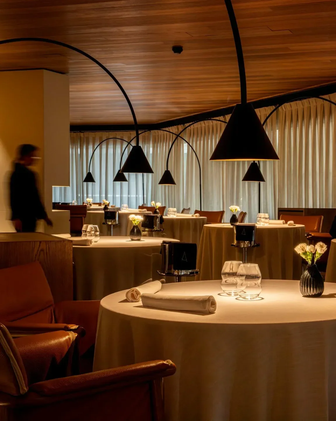 Elegant dining room interior at Angle restaurant in Barcelona, with round tables.