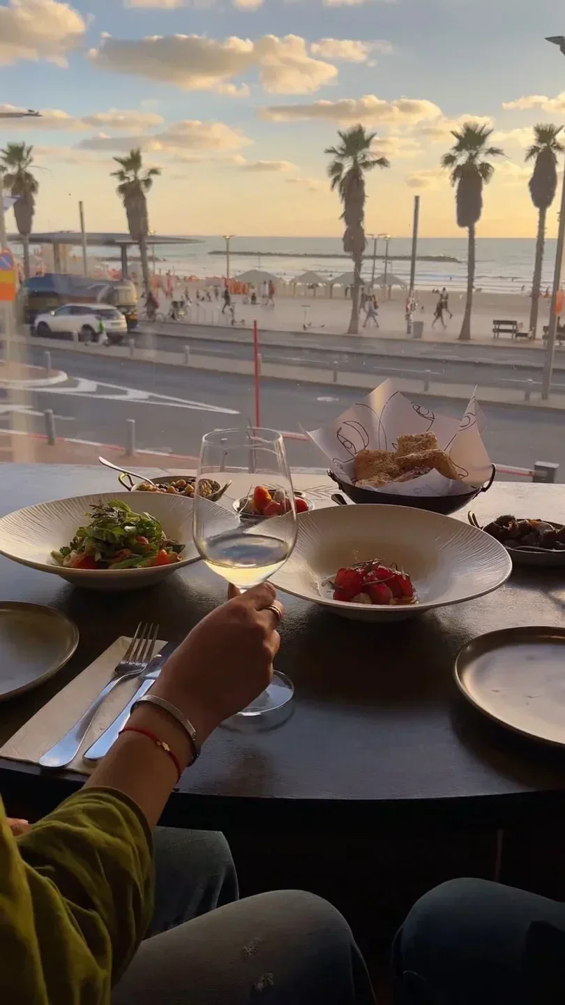 Dining at Animar restaurant in Tel Aviv, with a beach view and sunset lighting.