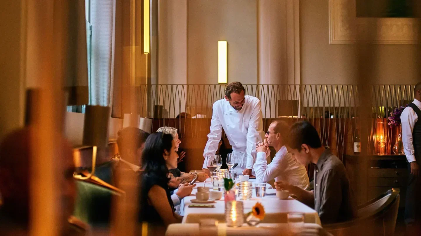 Chef at Anomaly SF in San Francisco speaks with guests at a dining table.