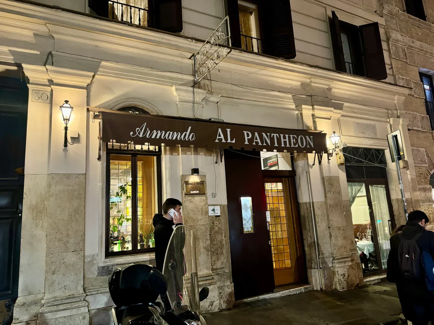 Exterior of Armando al Pantheon restaurant in Rome, at night with people.