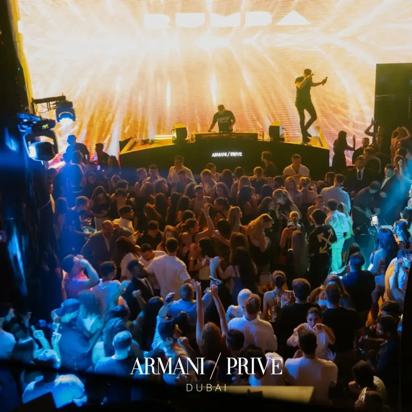 Energetic crowd at Armani/Prive nightclub in Dubai with DJ and stage lights.
