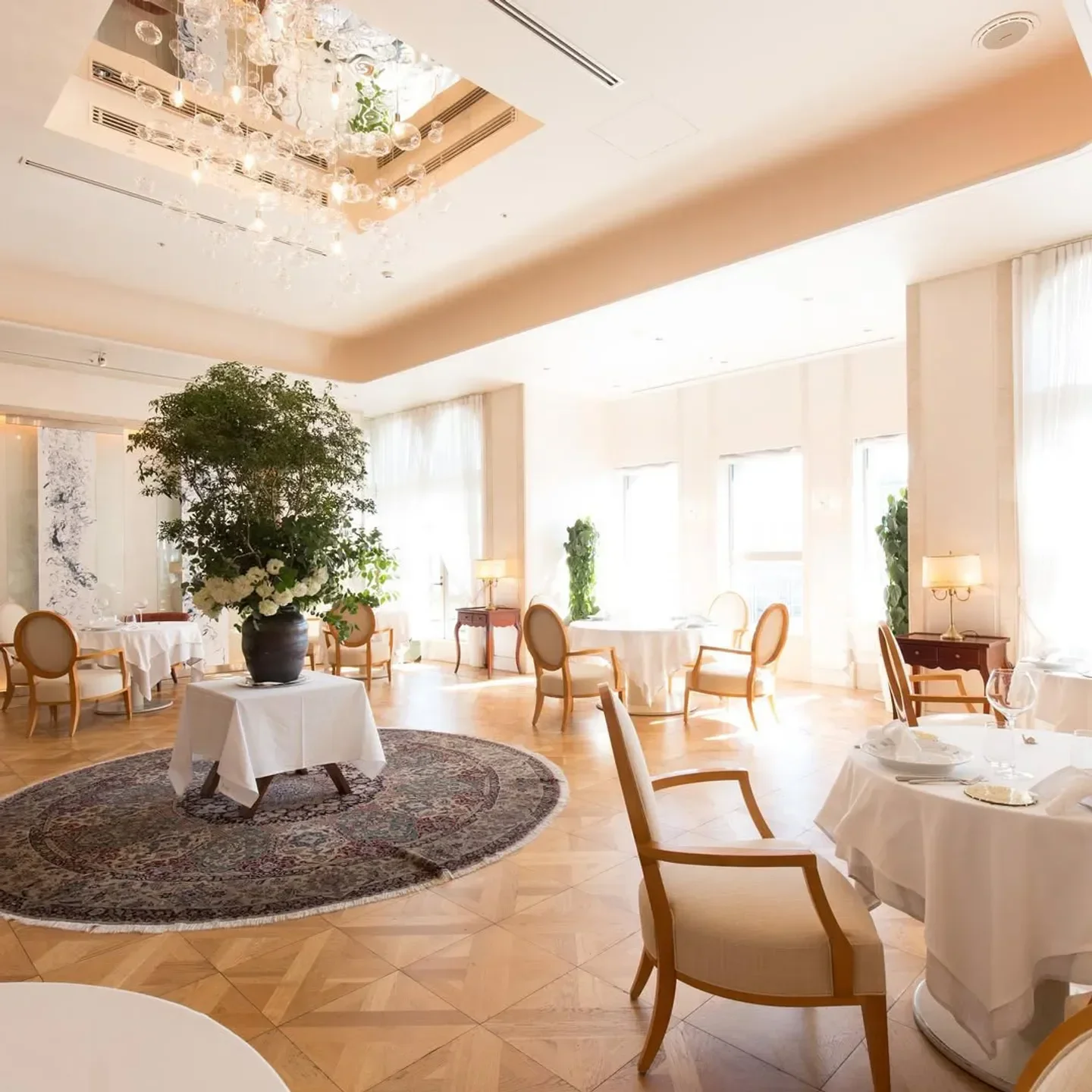 Elegant dining room interior at Aroma Fresca in Tokyo, featuring tables and a chandelier.