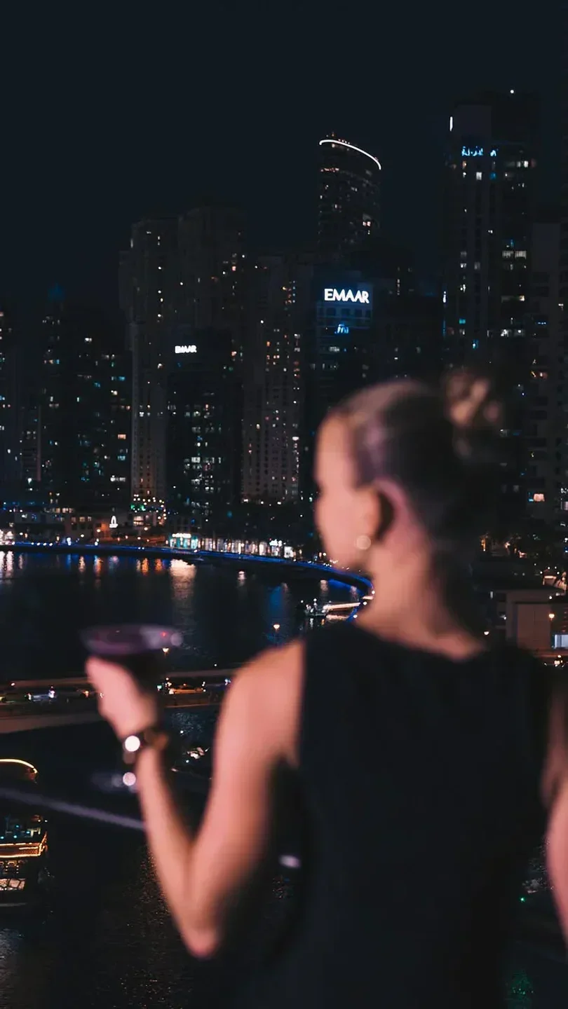 Night view from Asia Asia Business Bay in Dubai, a woman enjoying the city lights.