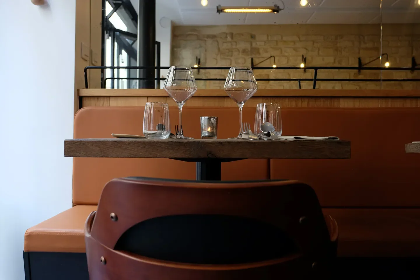 Table setting at Aspic restaurant in Paris, featuring glasses and a candle.