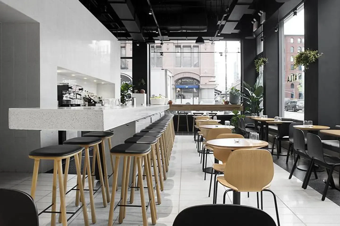 Minimalist interior of ATLA Noho in New York City with bar stools and tables.