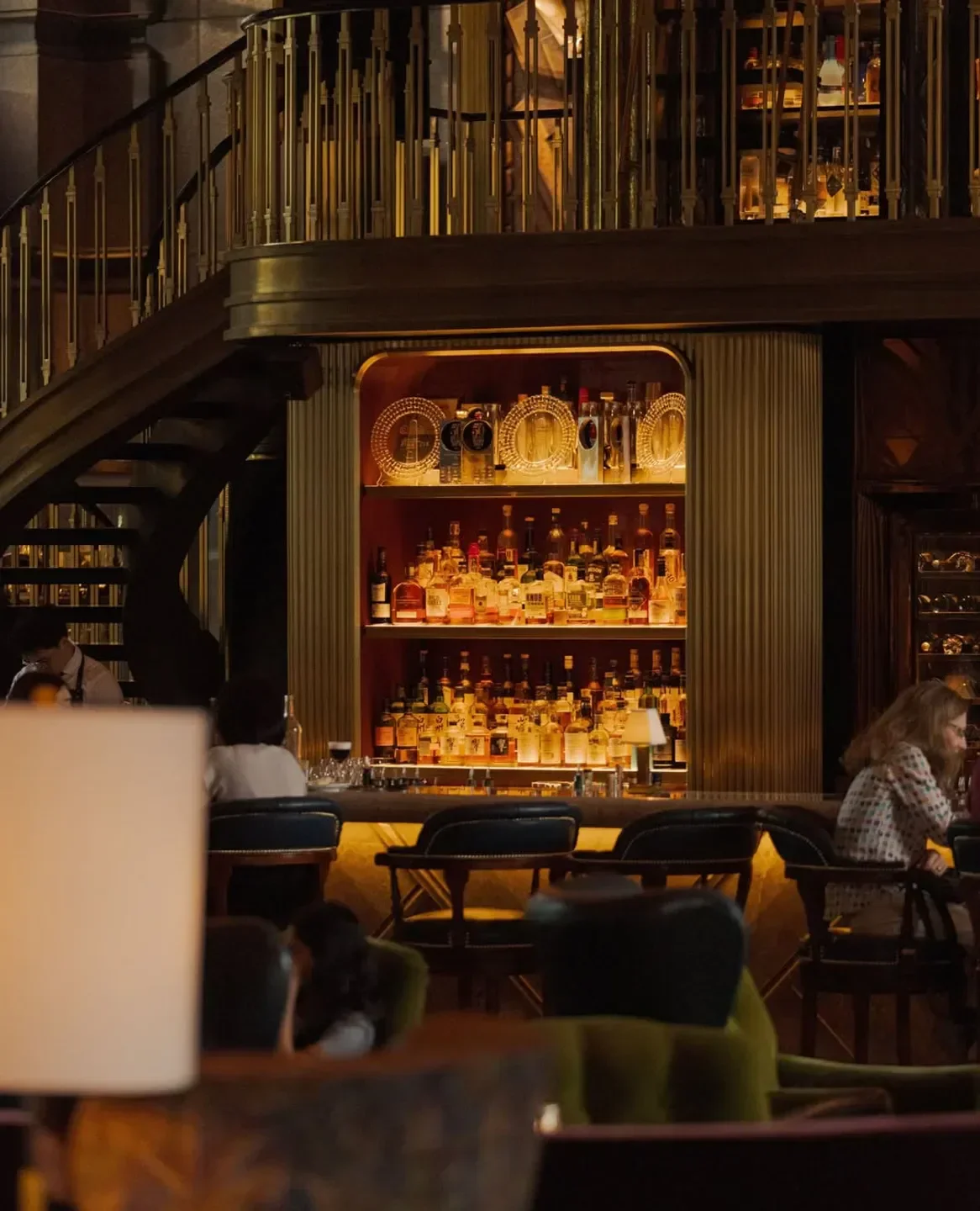 Interior of Atlas Singapore, a luxurious bar with spirits and seating near the staircase.