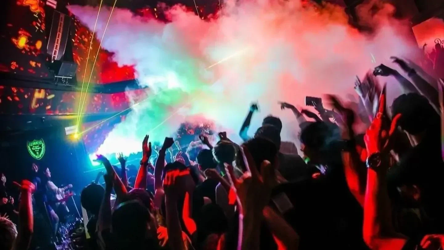 Energetic crowd at ATOM nightclub in Tokyo with colorful lights and atmosphere.