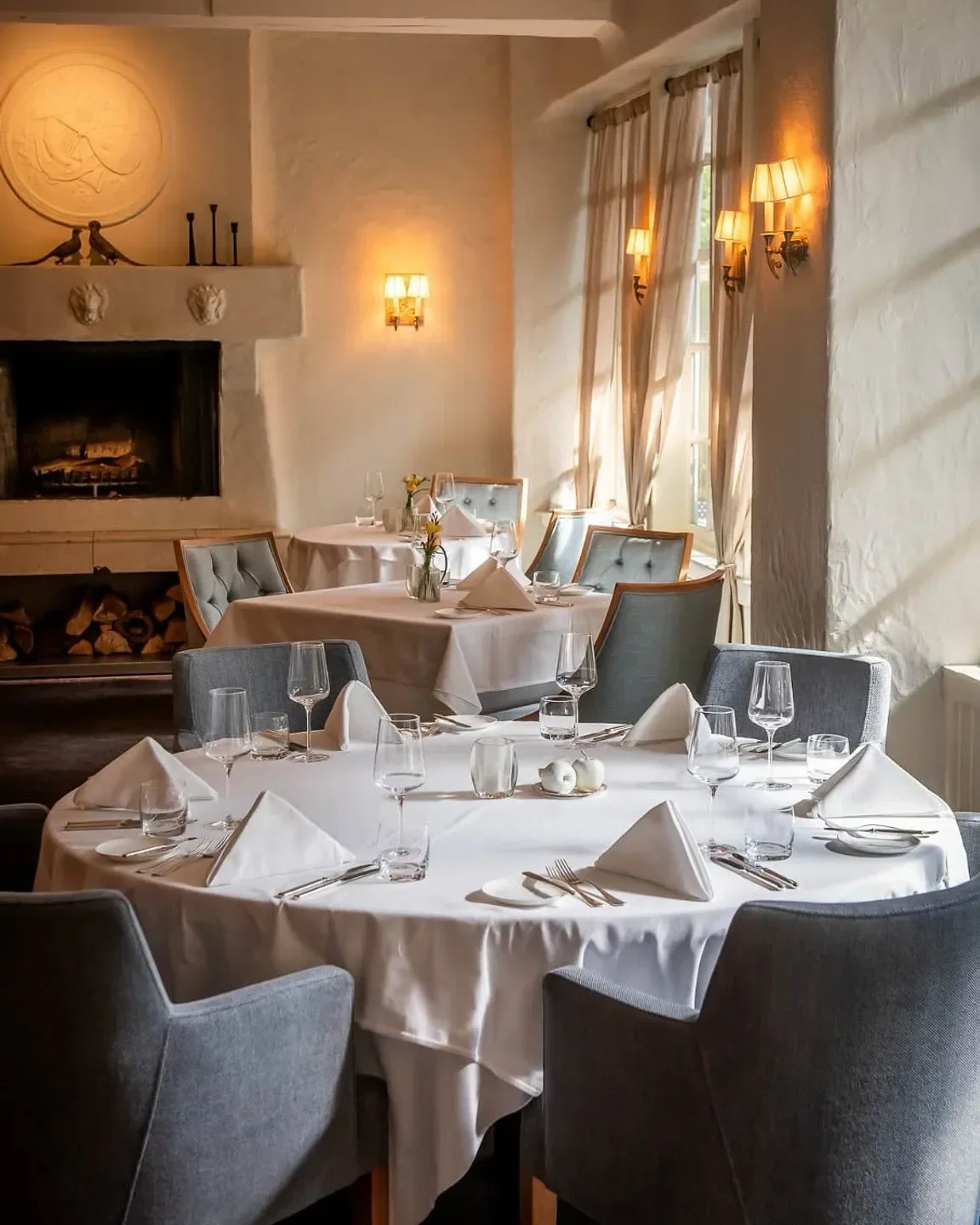 Elegant dining room at Auberge du Pommier in Toronto, featuring tables and a fireplace.
