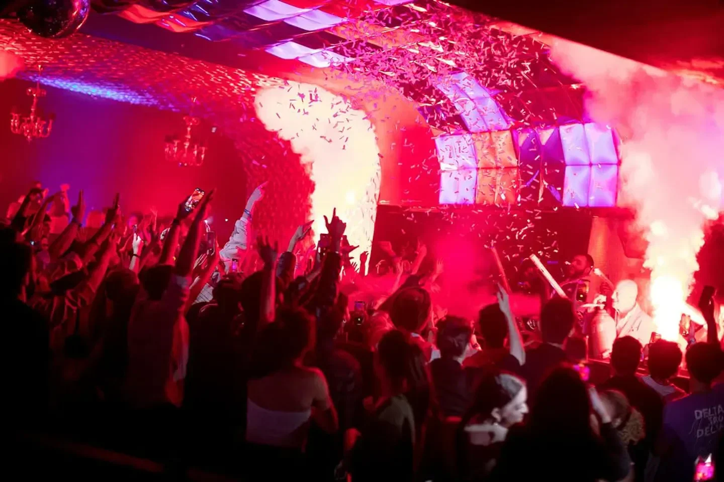 Energetic crowd at Aura Nightclub in Vancouver, with confetti and a vibrant light show.