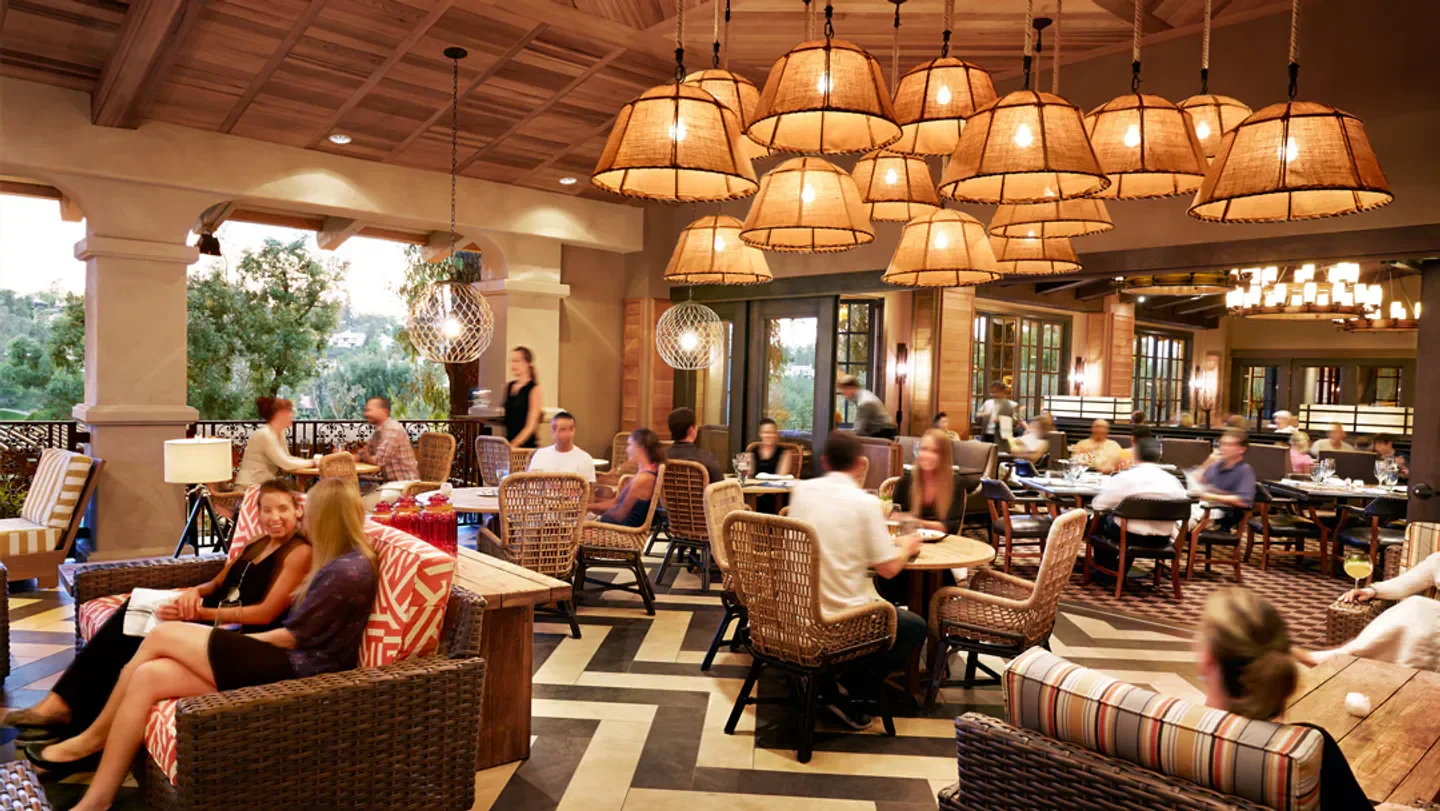 Interior dining at AVANT San Diego restaurant with wicker chairs and hanging lights