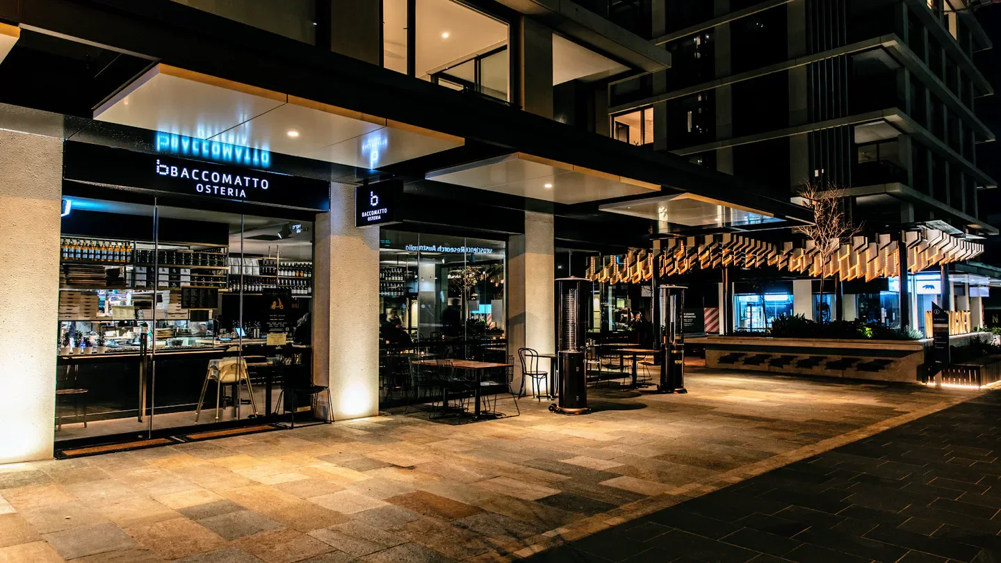 Exterior view of Baccomatto Osteria restaurant in Sydney at night, with outdoor seating.