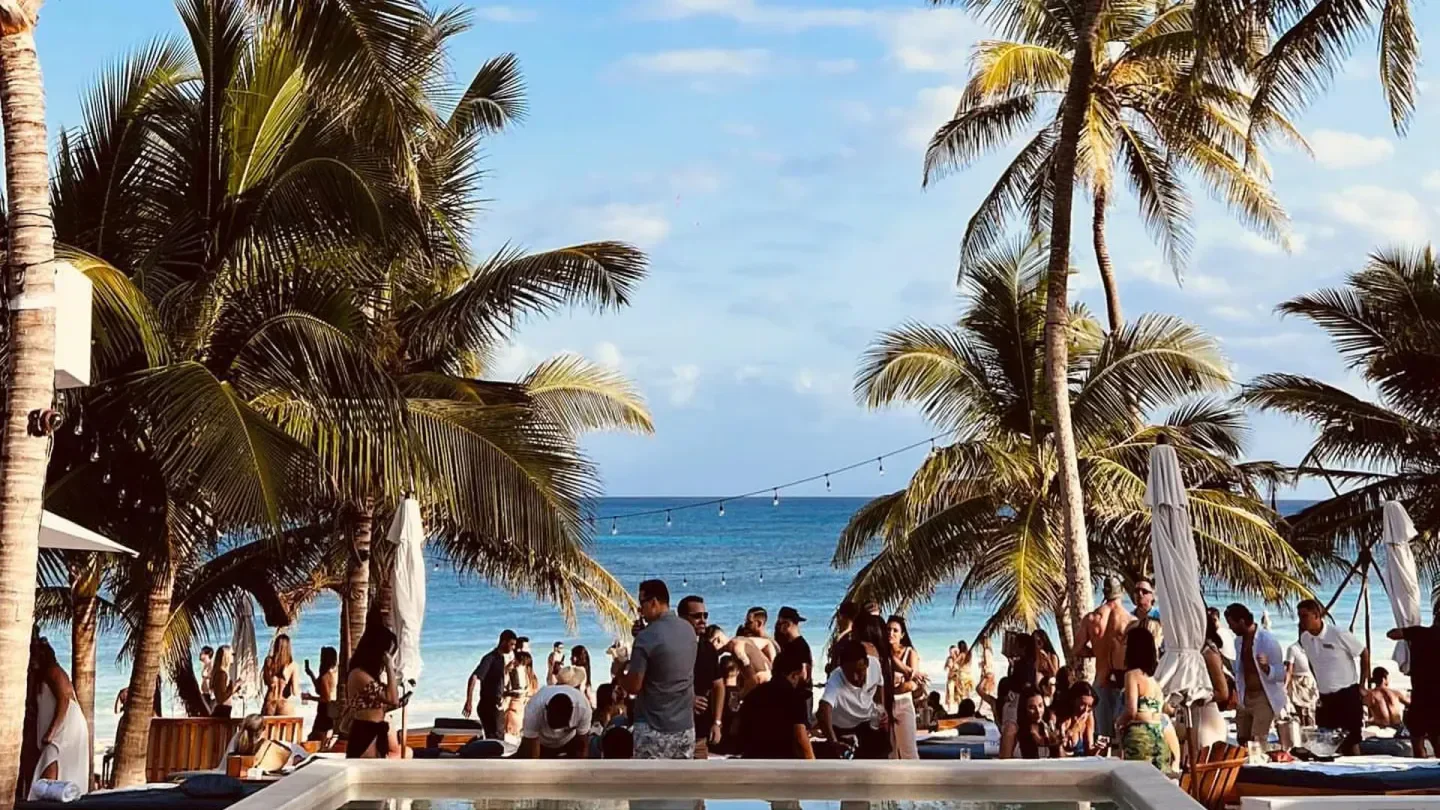 Beachfront scene at Bagatelle Tulum, people enjoying a sunny day by the ocean