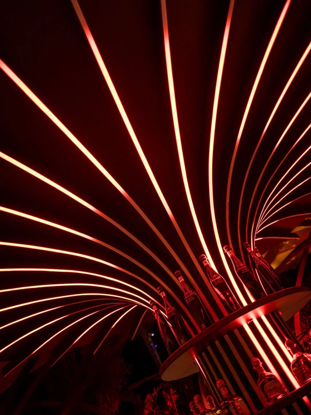 The striking red neon-lit interior ambiance of Baoli restaurant in Cannes, showcasing bottles on display.