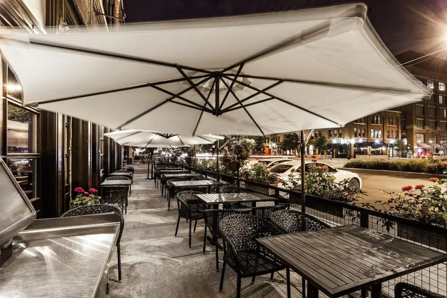 Outdoor dining at Bar Siena in Chicago, with tables under large umbrellas at night.