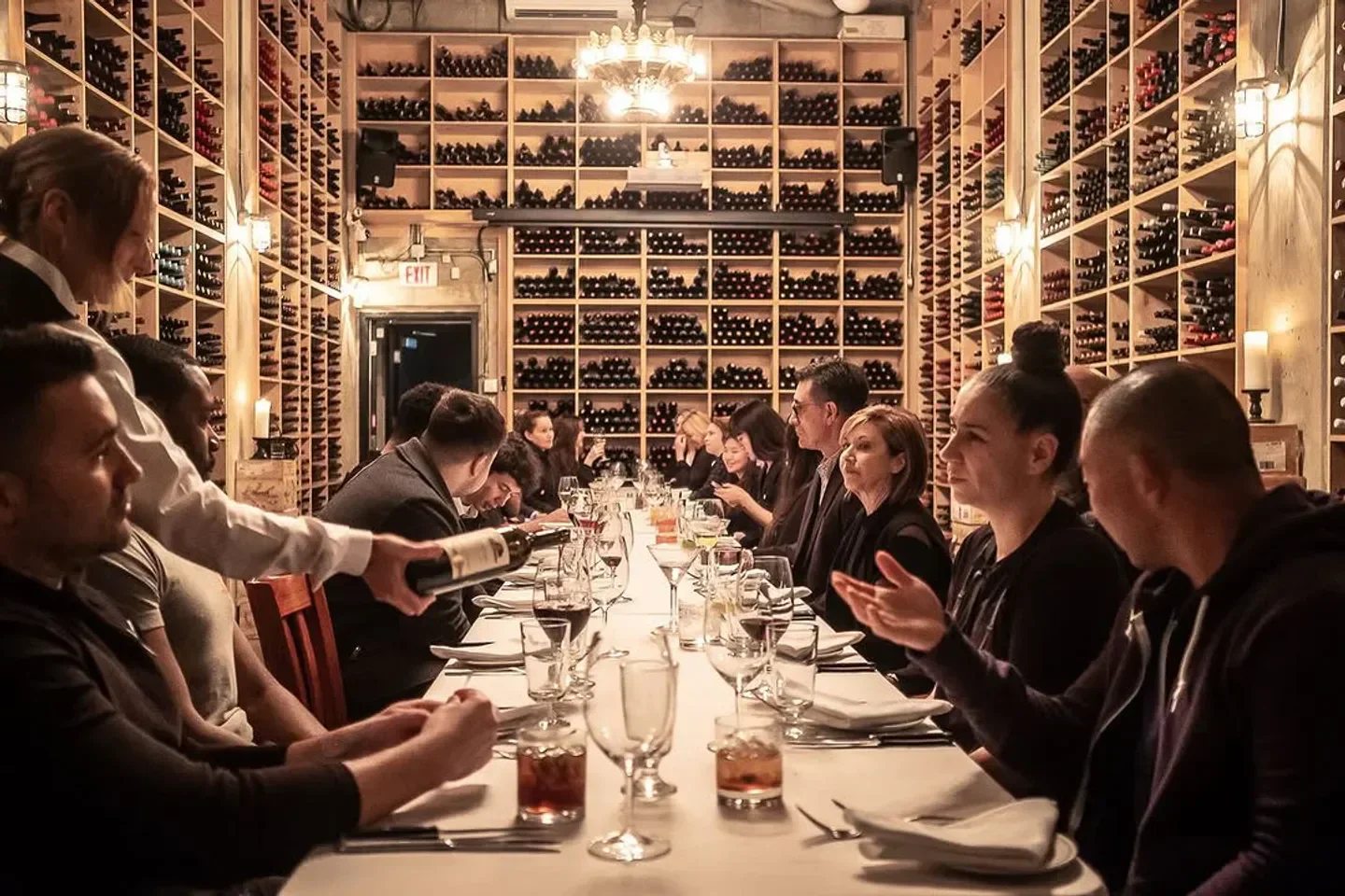 Dining at Barberian's in Toronto, waiter pouring wine, surrounded by wine racks.