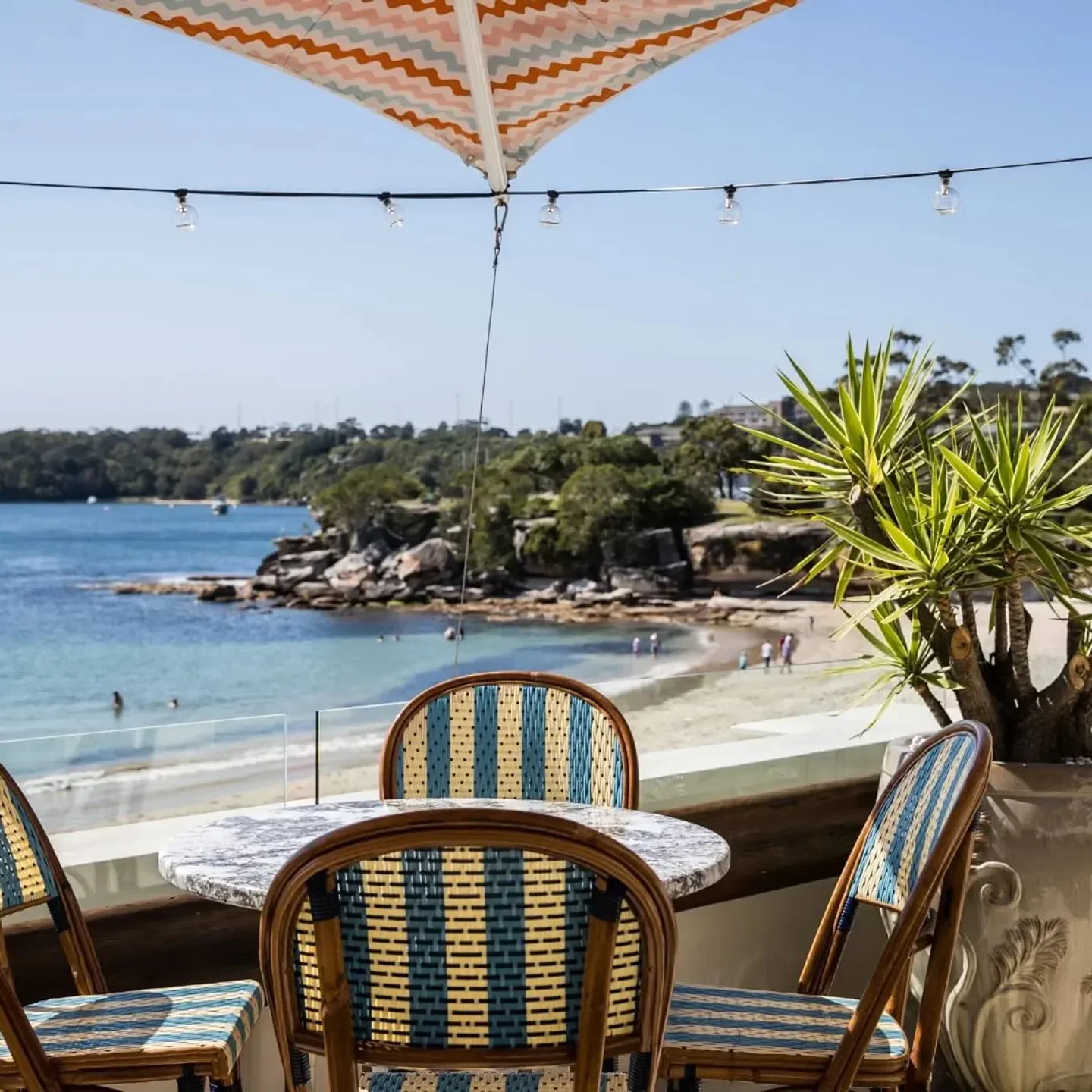 Outdoor seating at Bathers' Pavilion restaurant in Sydney with beach views on a sunny day