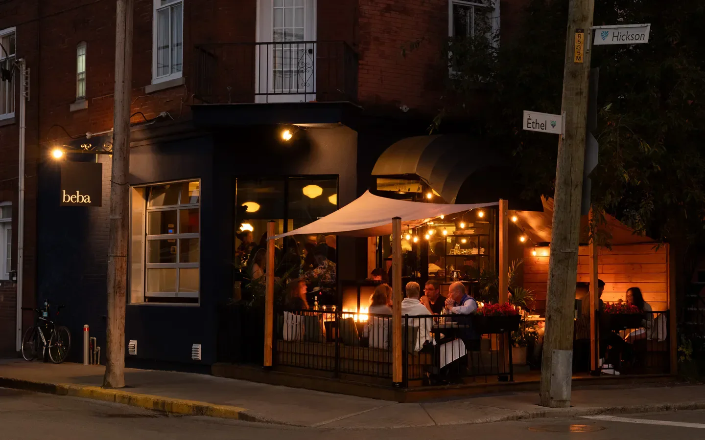 Outdoor dining at Beba restaurant in Montreal, with cozy lighting and happy patrons.