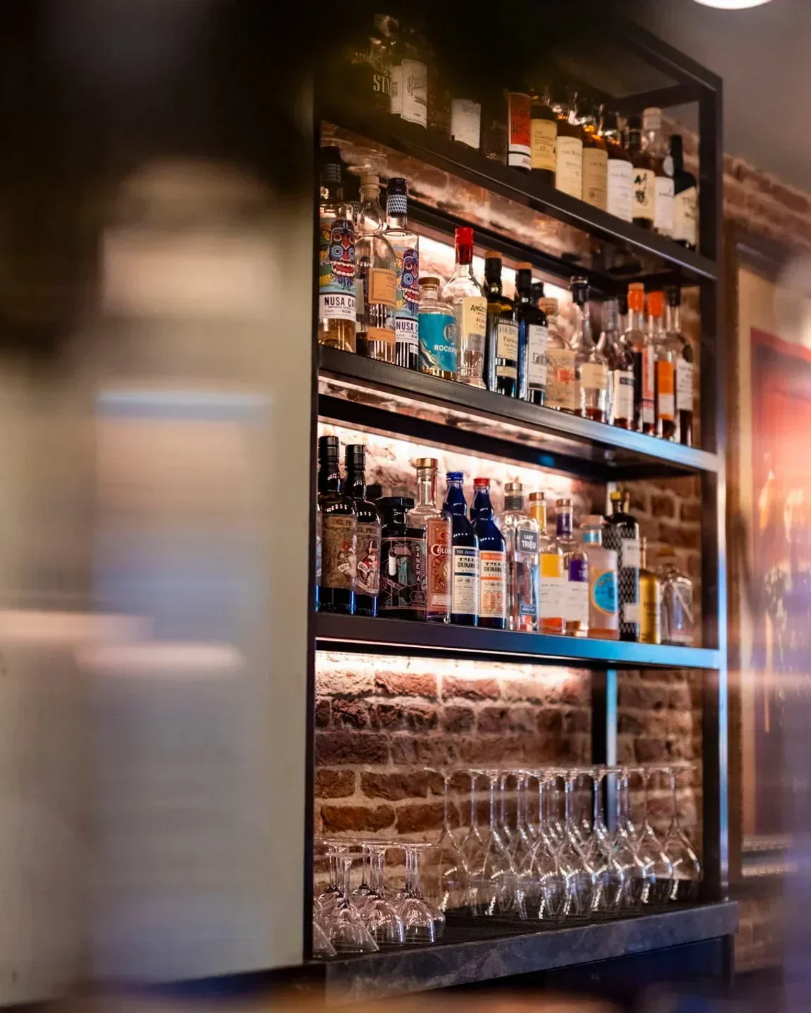 Well-stocked bar at Bistecca Tuscan Steakhouse in Singapore, featuring spirits and glassware.