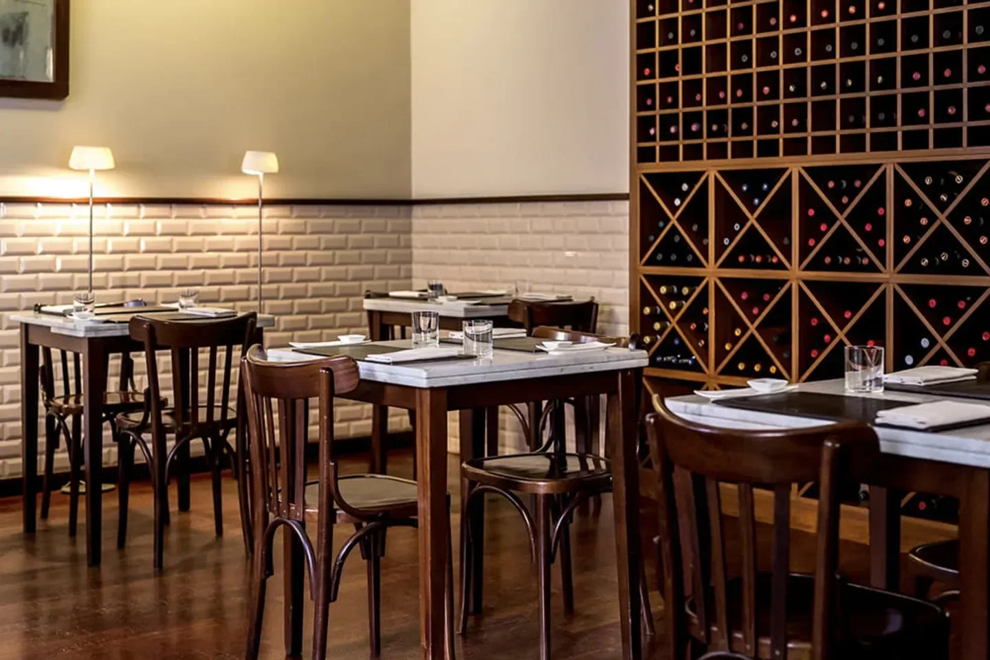 Cozy dining room at Bistrot 64 in Rome, featuring tables, chairs, and wine rack.