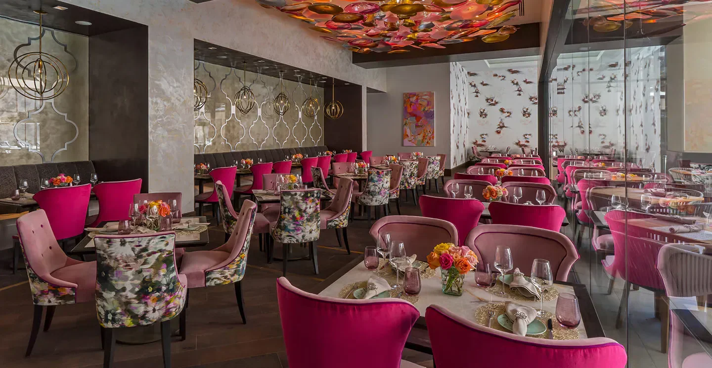 Elegant dining room at Bloom & Bee in Houston with floral decor and pink accents.