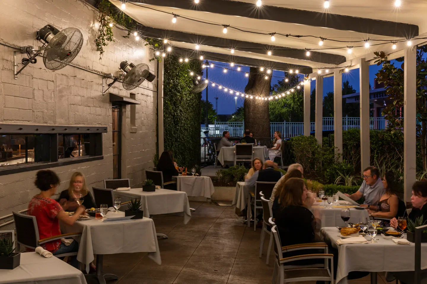 Outdoor patio dining at Bludorn in Houston, with string lights and happy diners.