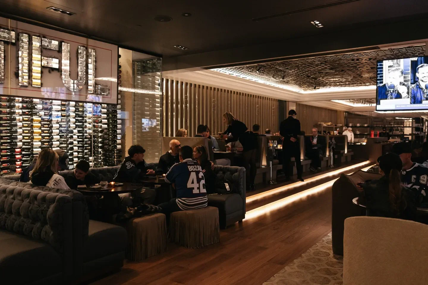 Interior of Blue Bovine Steak Sushi House in Toronto, with diners and a wine display.