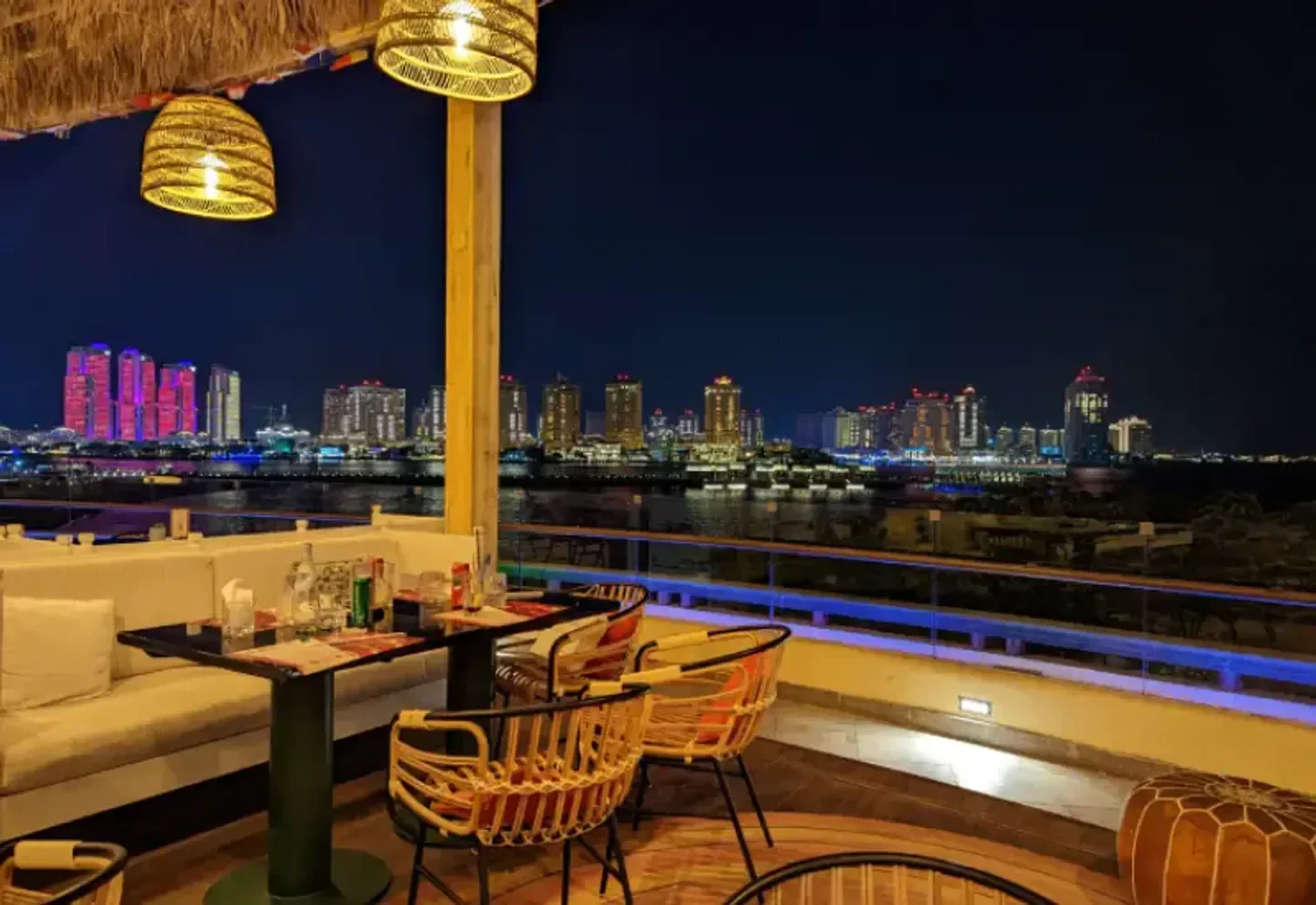 Boho Social in Doha, elegant terrace with city skyline view at night.
