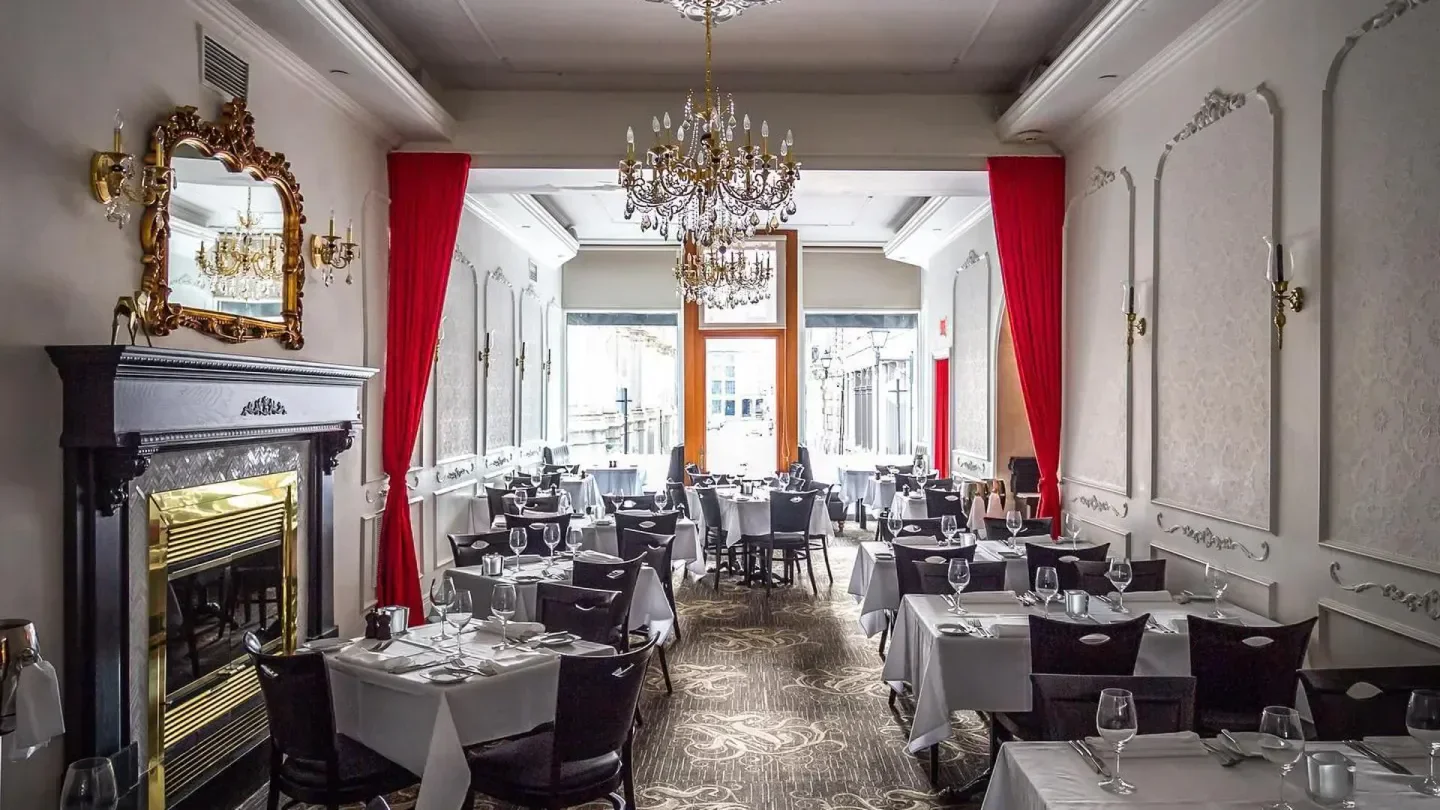 Elegant dining room at Bonaparte restaurant in Montreal, with chandeliers and red curtains.