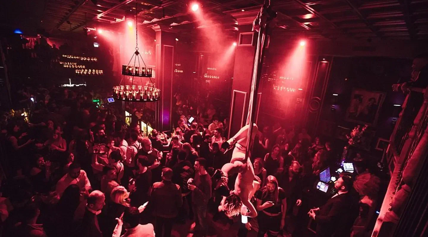 Bord'Elle nightclub in Montreal with a performer on a pole surrounded by a crowd.