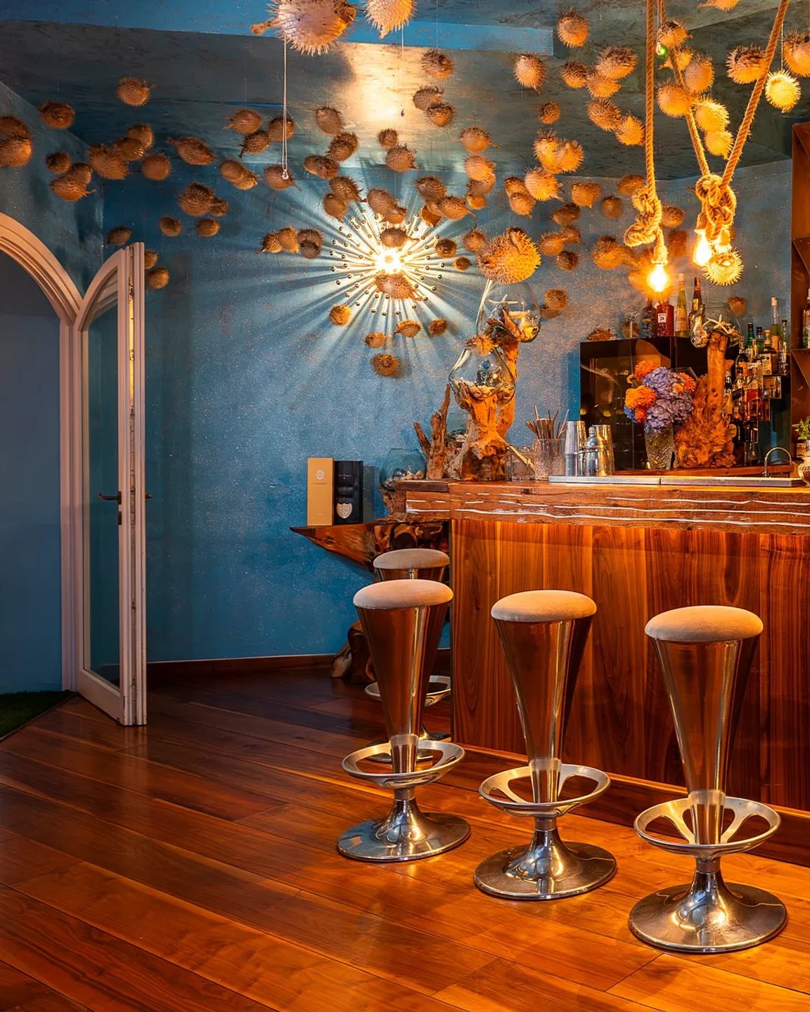 Bubble Bar & Bistrot Porto Cervo interior features unique pufferfish decor and a polished wooden bar with elegant stools.