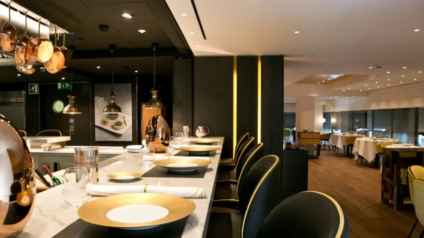 Elegant dining space at Caelis restaurant in Barcelona, with golden accents and marble bar.