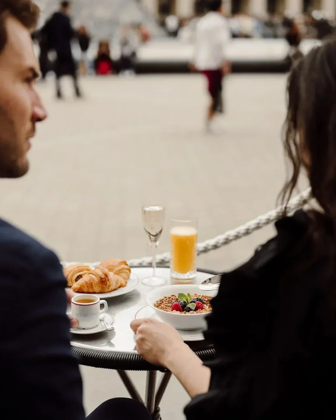 Breakfast at Café Marly, Paris. Couple enjoying pastries and coffee outdoors.