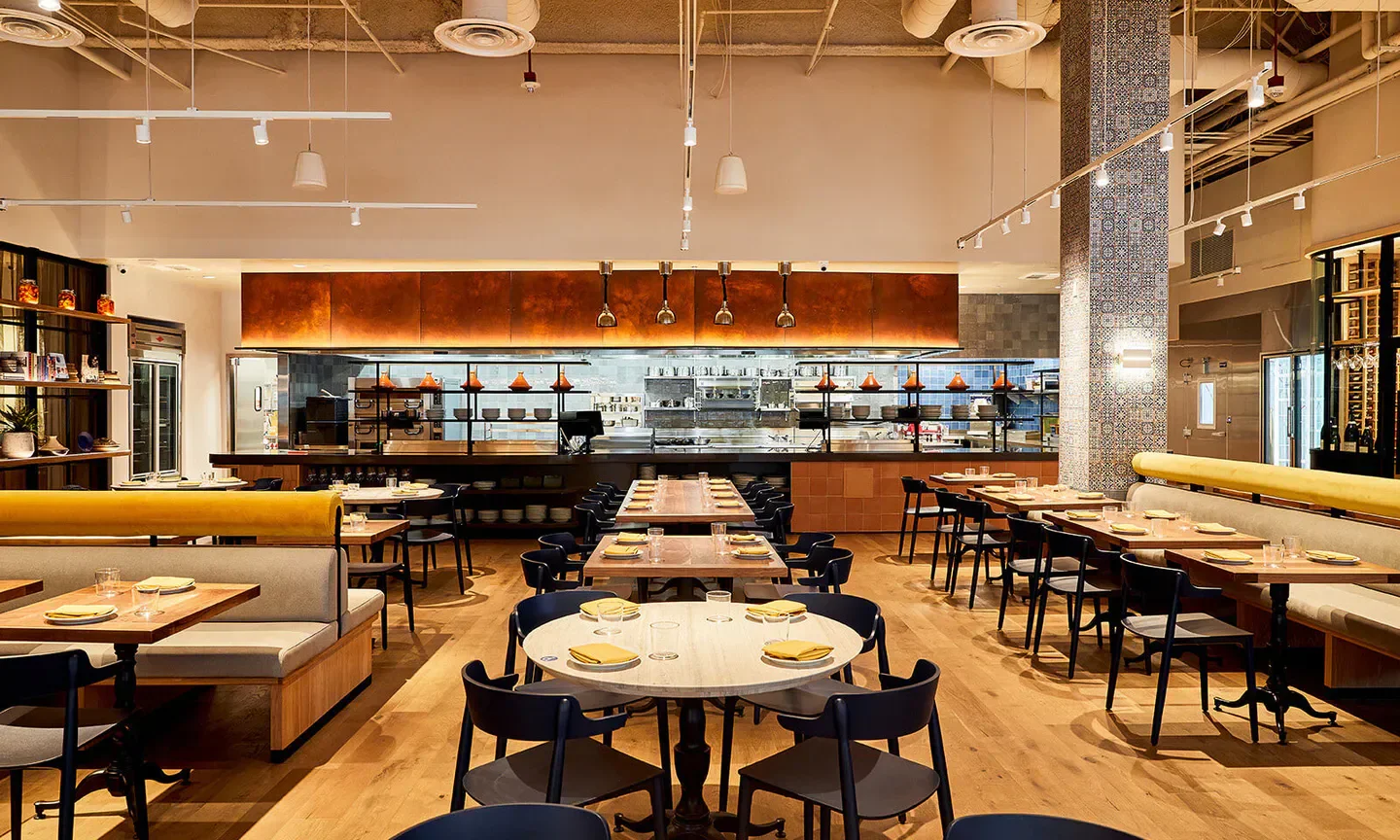 Interior of Callie restaurant in San Diego featuring tables, chairs, and kitchen view