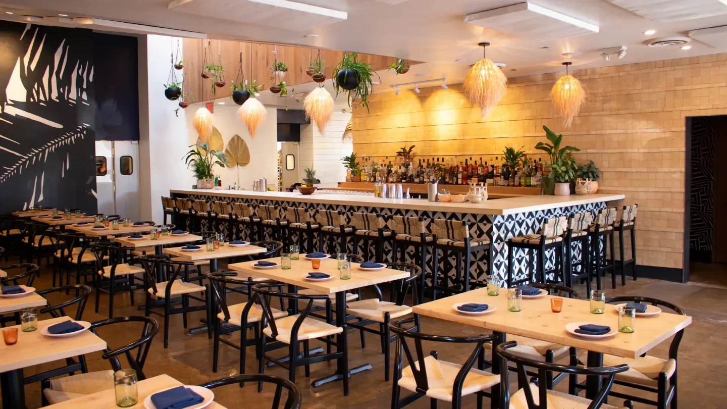 Interior dining space at Canje restaurant in Austin with bar and hanging decor.