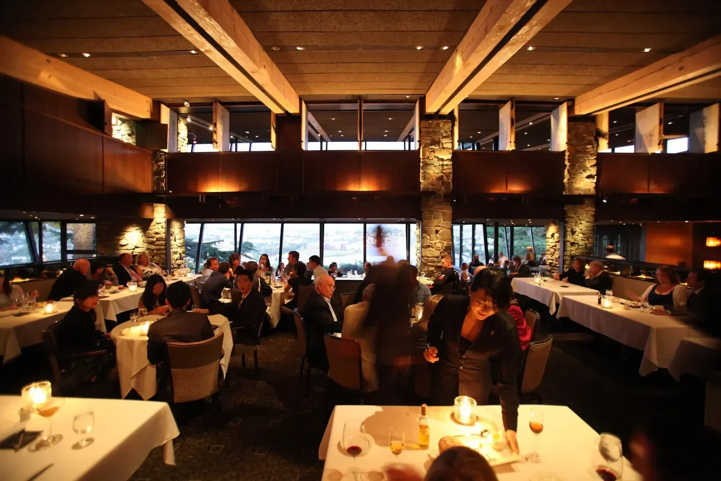Elegant dining room at Canlis restaurant in Seattle, filled with people enjoying dinner
