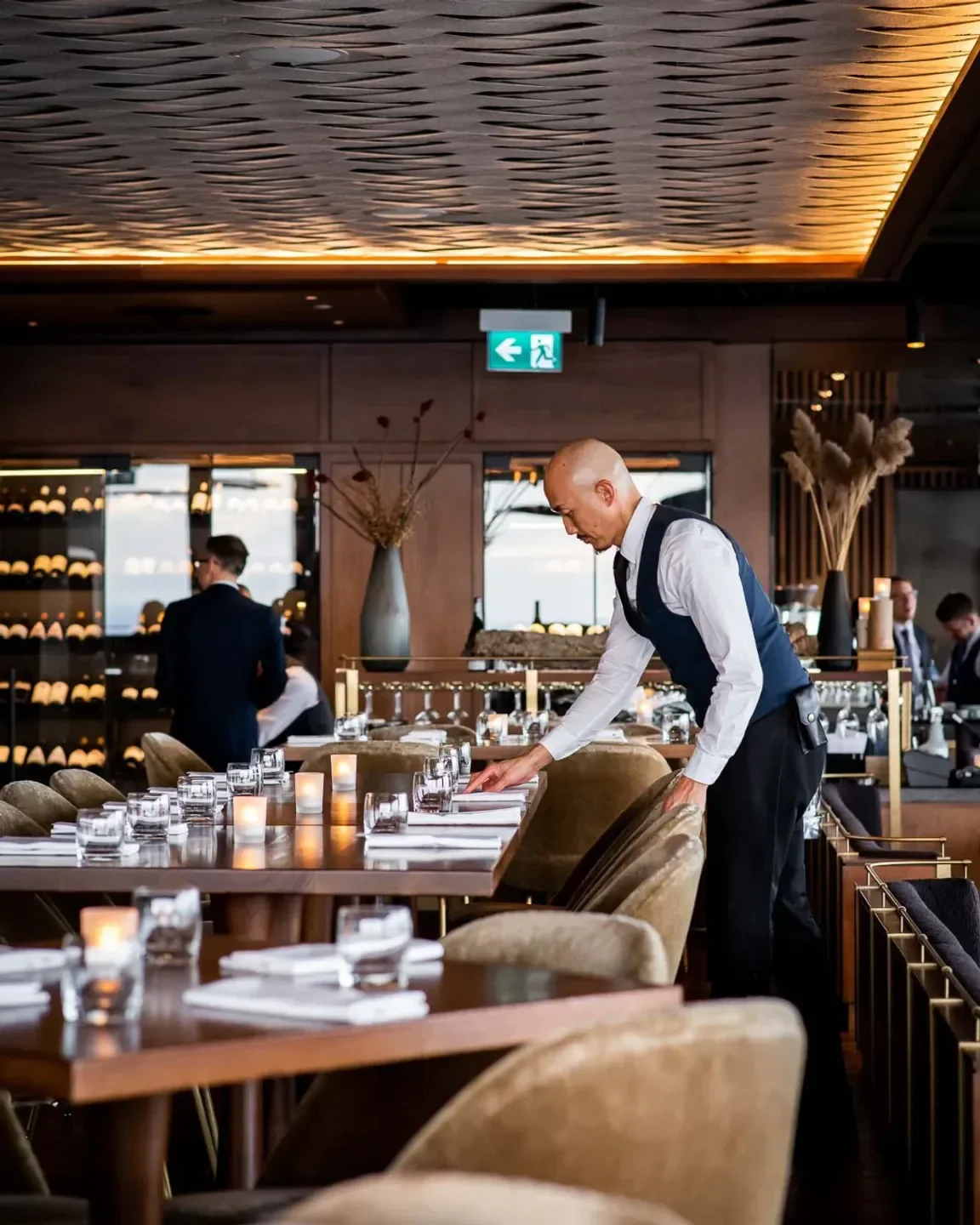 Server sets table at Canoe restaurant in Toronto, showcasing elegant interior details.