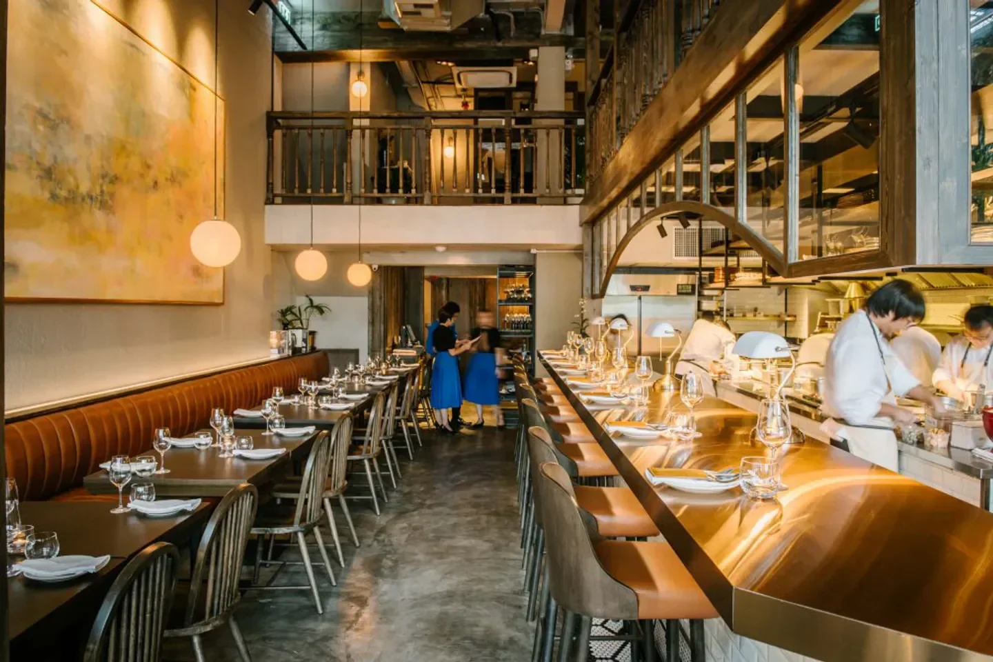 Interior of Canvas restaurant in Bangkok, showcasing bar, dining tables, and kitchen.